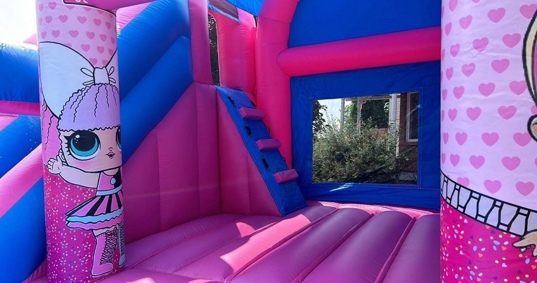 Bright pink and blue inflatable bounce house with cartoon character designs.