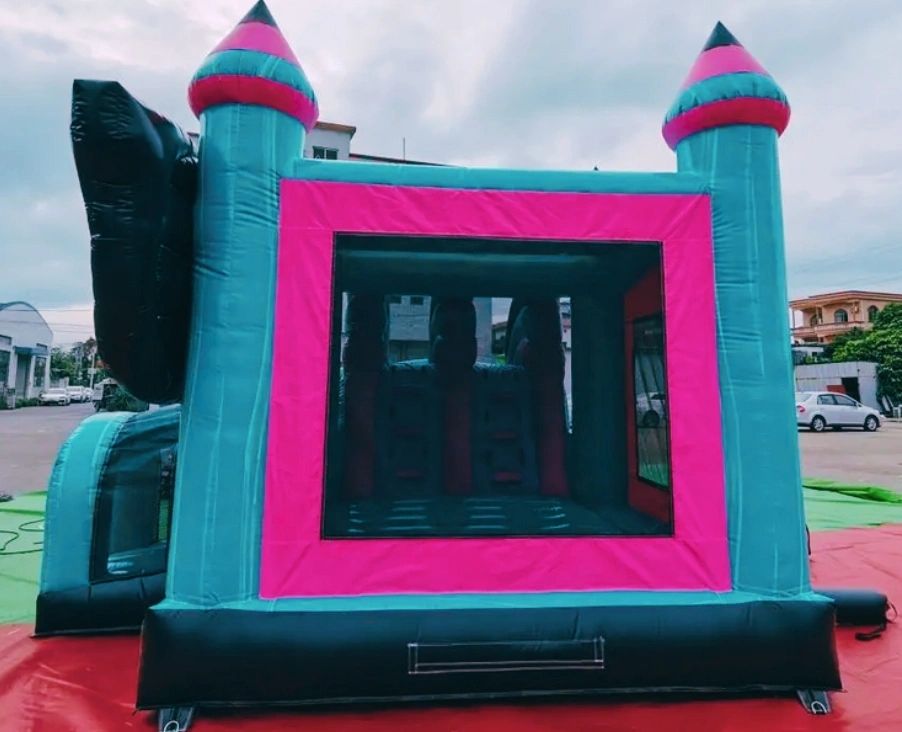 A colorful inflatable bounce house set outdoors on a red and green mat.