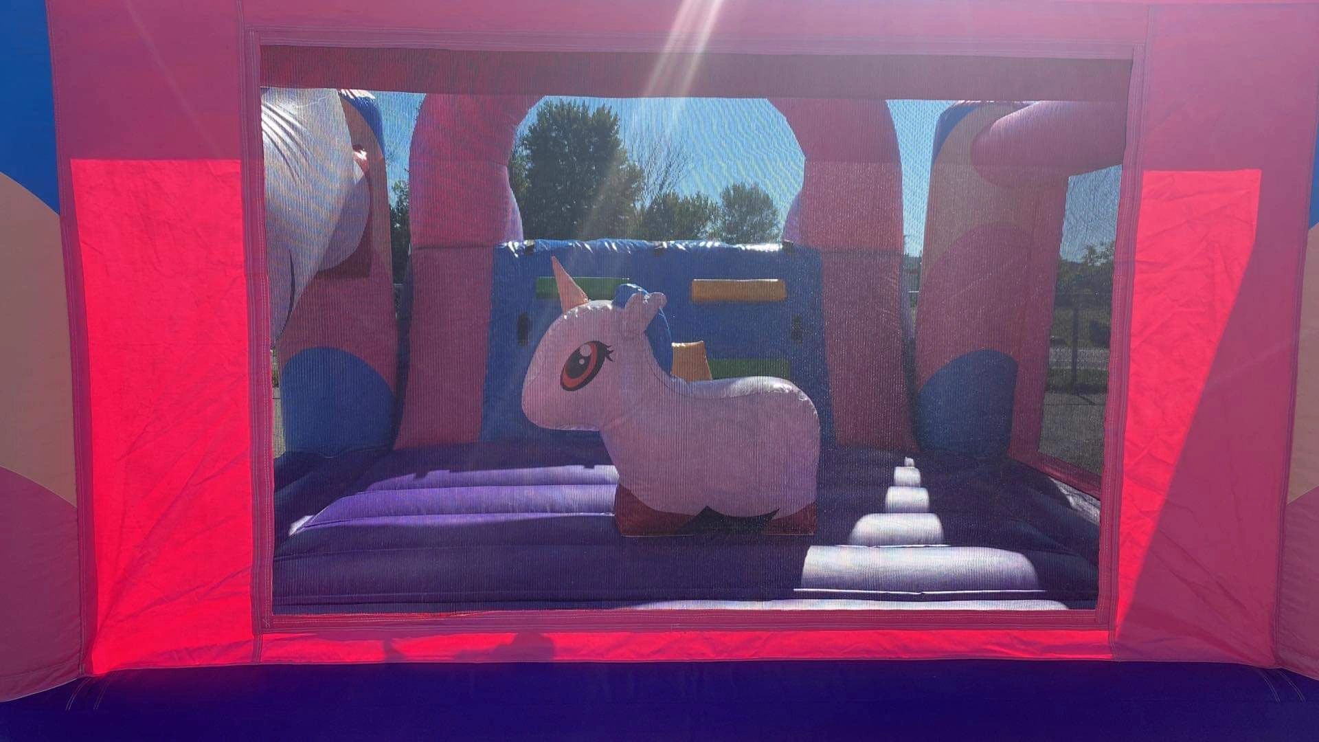View inside a colorful inflatable bounce house with a unicorn figure.