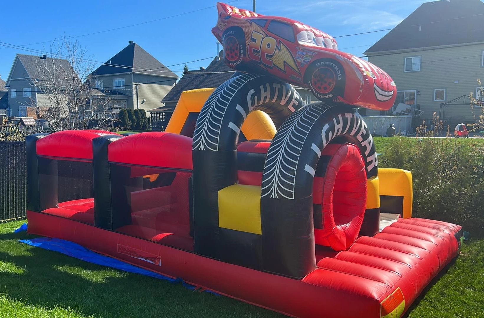 Inflatable bounce house with a racing car theme in a backyard.