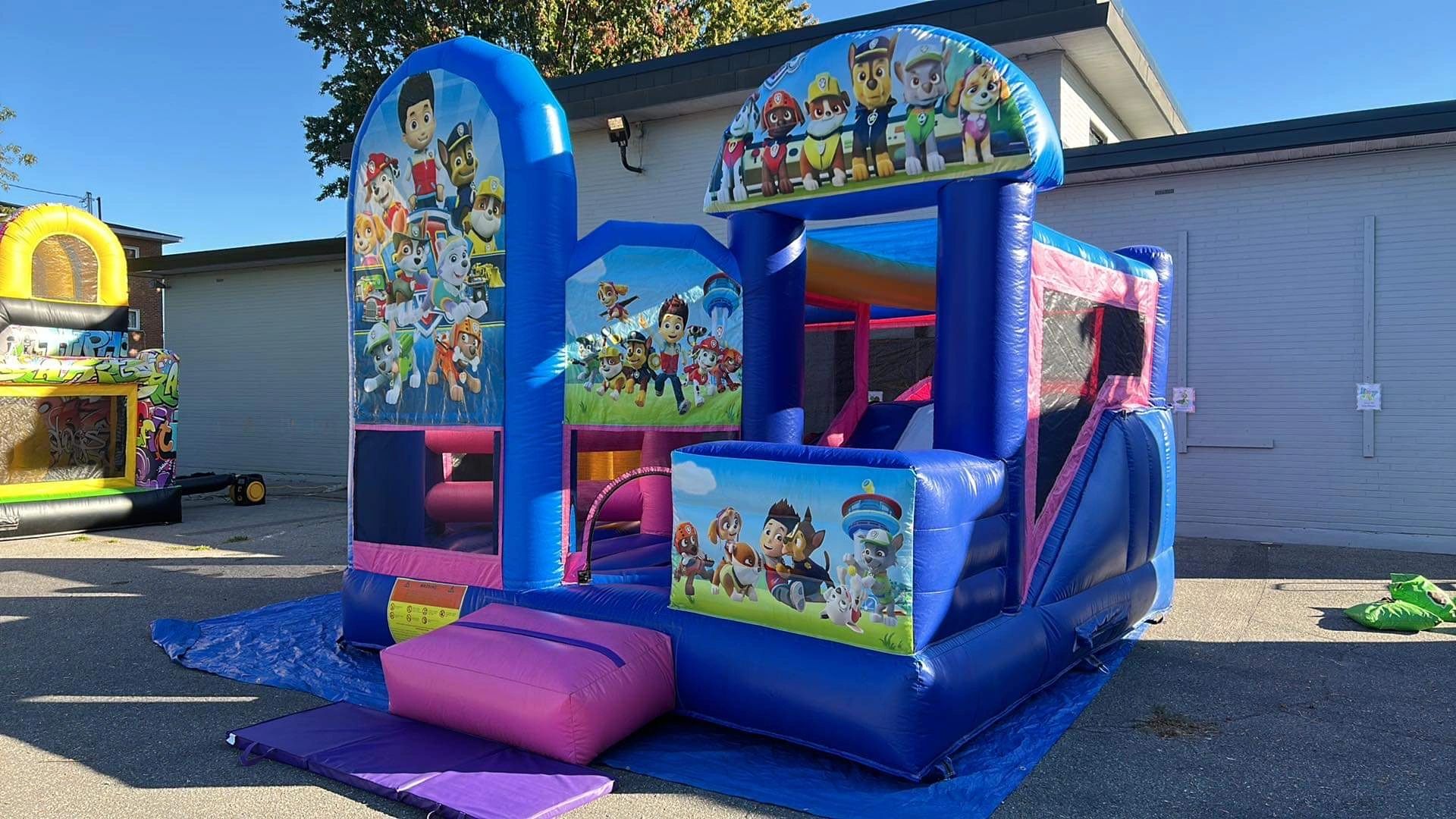 Colorful Paw Patrol-themed inflatable bounce house outdoors on a sunny day.