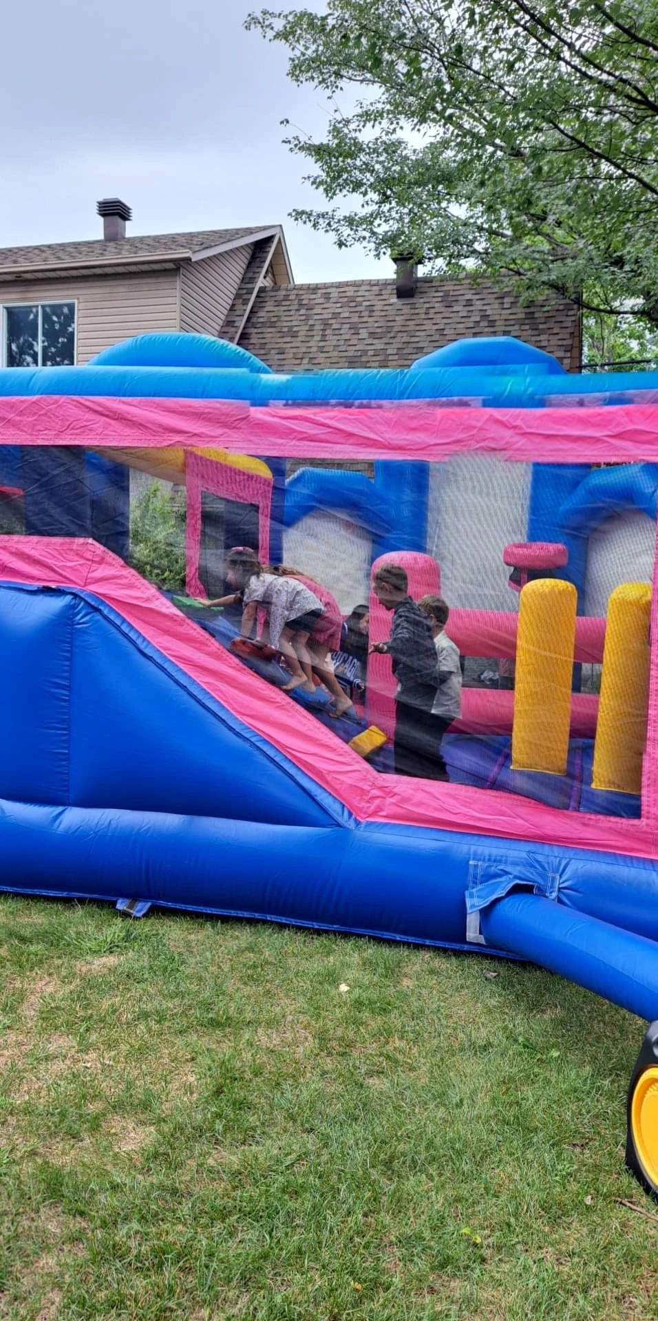 Children playing inside a colorful inflatable bounce house in a backyard.