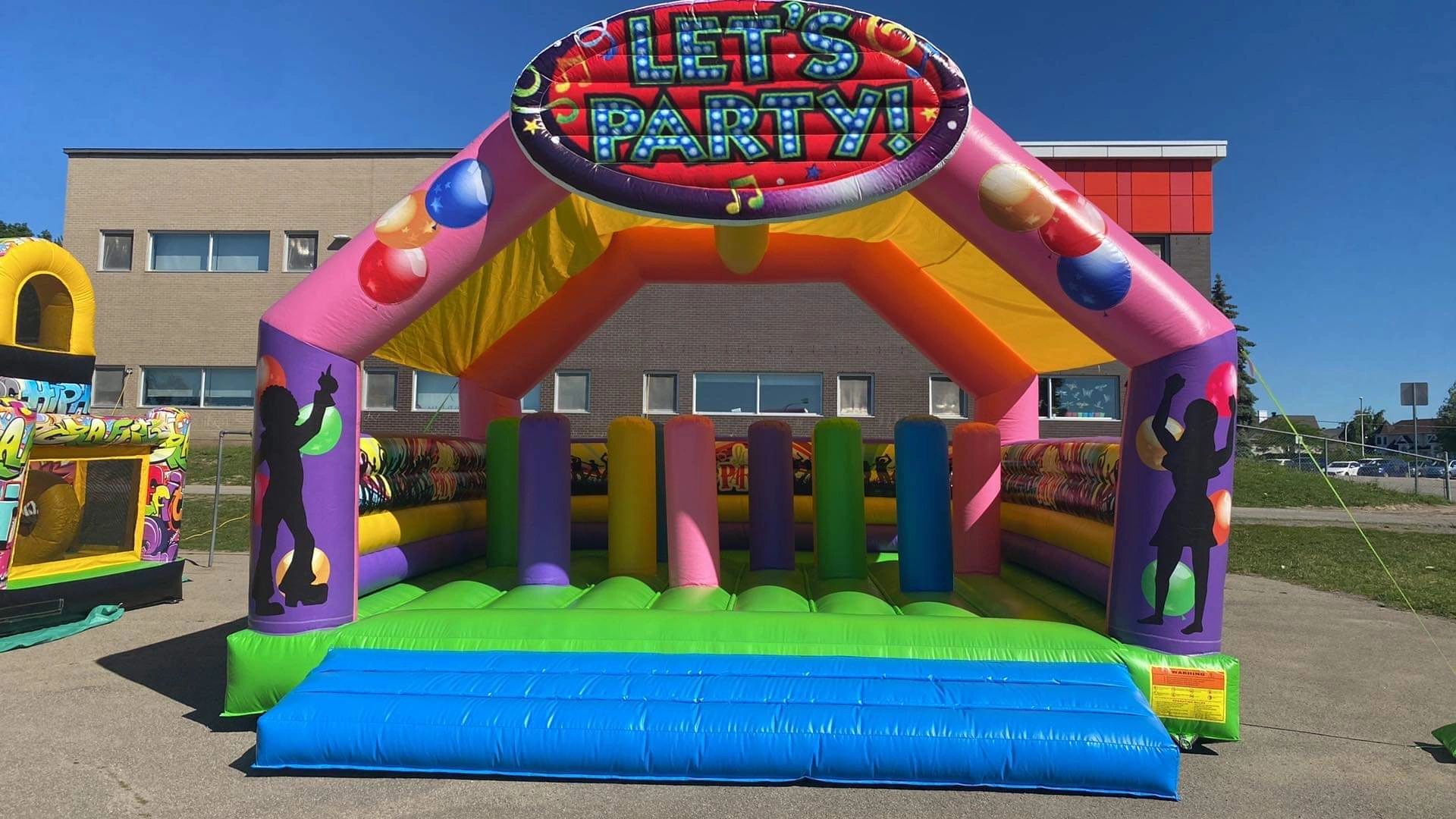Colorful inflatable bounce house with a 'LET'S PARTY!' sign on top.