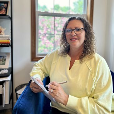 Naomi Kreske sitting in her blue chair writing notes