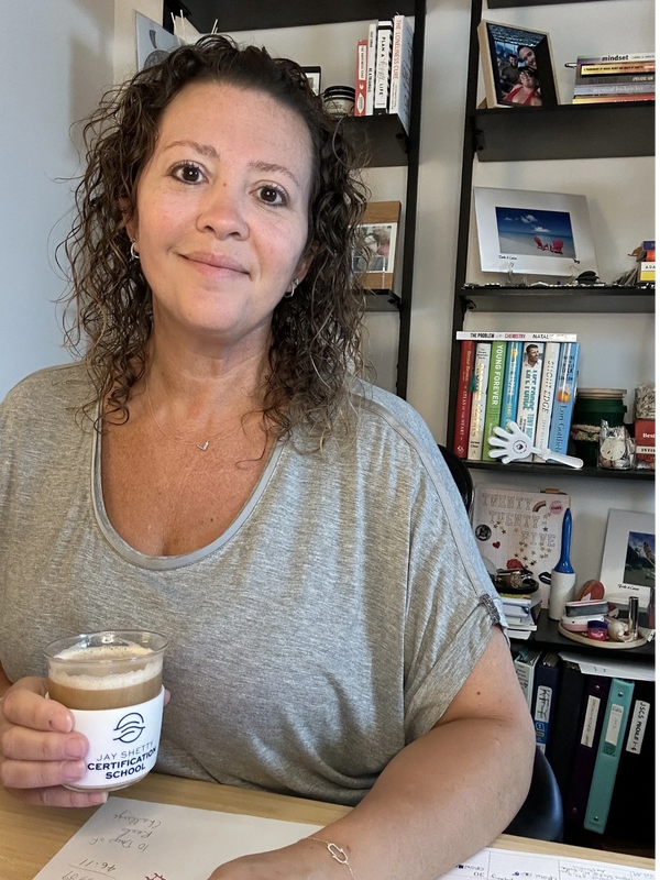 Naomi Kreske sitting at her desk drinking coffee