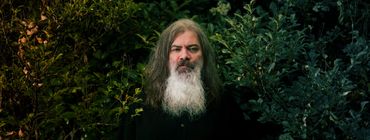Brent Best stands among foliage for a professional portrait by Christi LaViolette.