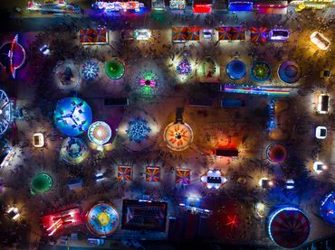 A top down aerial view of the Denton County Fair at night with neon lights and rides.