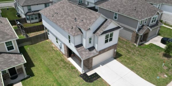 A modern two-story house with a driveway and green lawn in a suburban neighborhood.