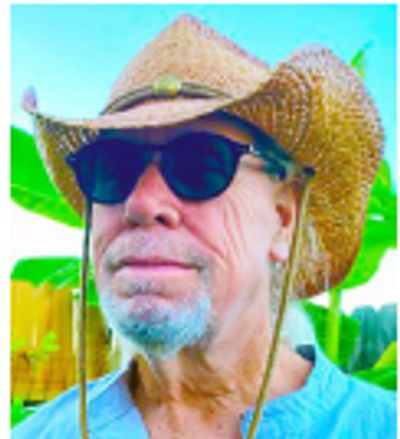 Older man wearing sunglasses and a straw cowboy hat outdoors.