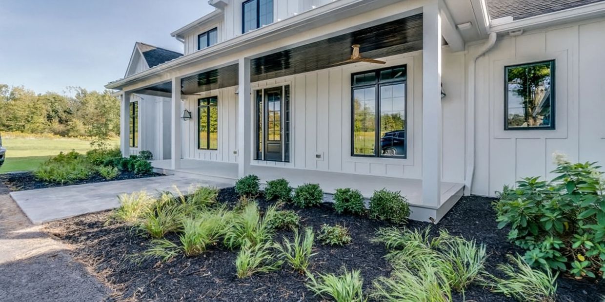Modern farmhouse-style home with a spacious front porch and landscaped garden.