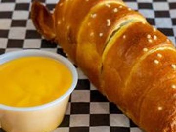 Pretzel-wrapped hot dog with cheese sauce.