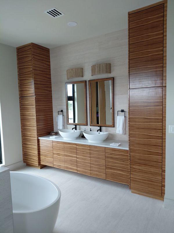 Modern bathroom with wooden cabinets, dual sinks, and a bathtub.