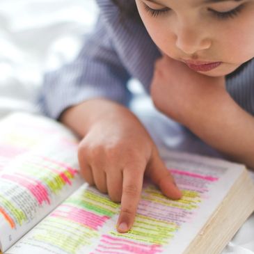 Child reading a heavily highlighted book with focus.