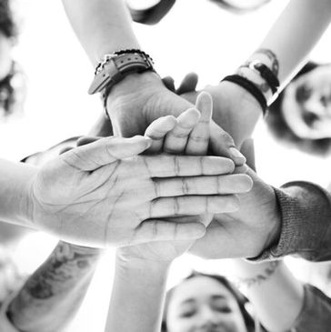A group of people stacking hands in unity, black and white.
