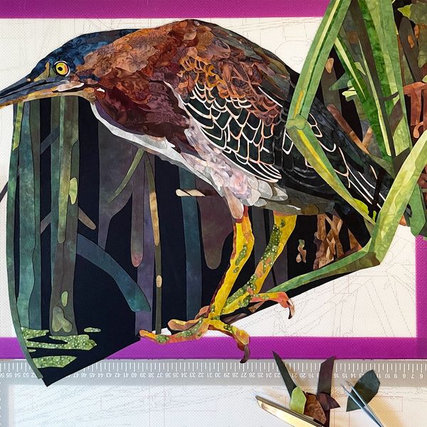 Colorful bird artwork in progress with scissors and ruler nearby.