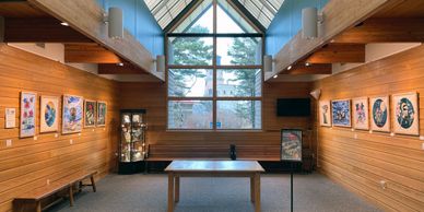 Art show installed on wood walls in a gallery with a large window