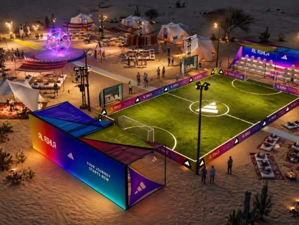 A vibrant nighttime desert football field with colorful tents and seating areas.