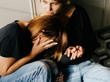 A comforting embrace between two people, one in distress.