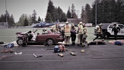 Emergency responders attend a car crash on a sports field.