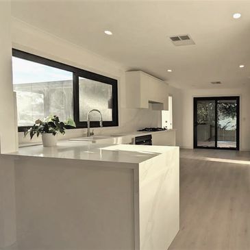 brand new open-plan  white kitchen renovation with waterfall Calcutta stone benchtop.