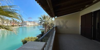 Spacious balcony overlooking turquoise water and palm trees under a clear blue sky.