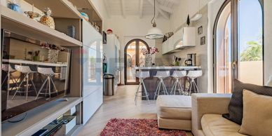 Modern open kitchen and living area with beige tones and arched windows.