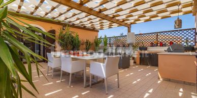 Spacious outdoor patio with dining area and pergola providing shade.