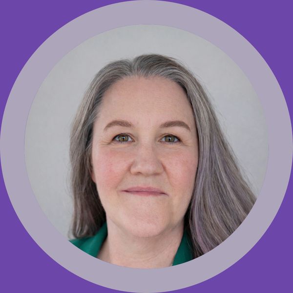 Portrait of a smiling middle-aged woman with gray hair and a green top.