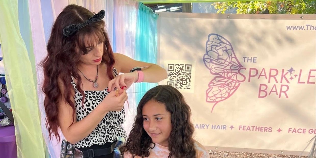 A team member from The Sparkle Bar tying in fairy hair at an event in Charleston, SC.