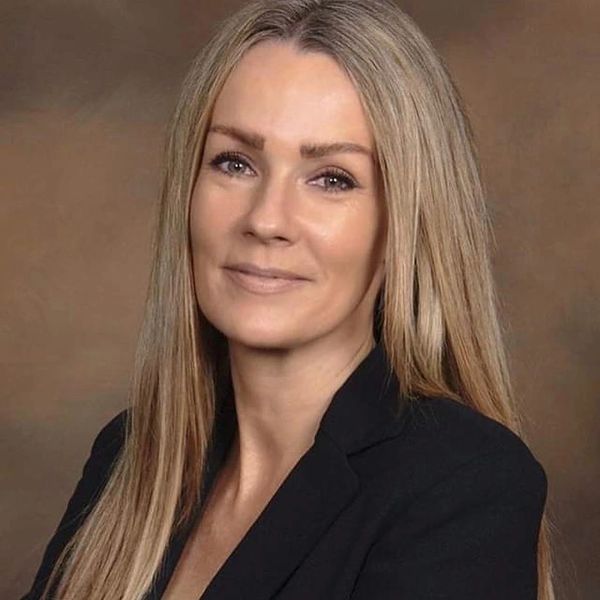 Professional portrait of a smiling woman with long blonde hair and black blazer.
