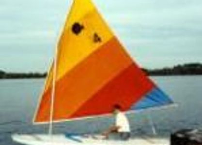 A small sailboat with a colorful sail on calm water.