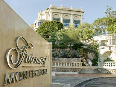 The Fairmont Monte Carlo hotel entrance with elegant architecture and greenery.