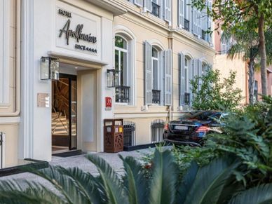Entrance of a classic hotel with elegant architecture and greenery.