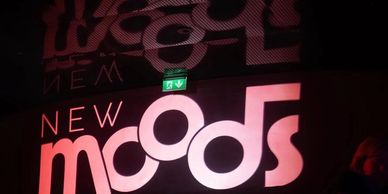 Illuminated sign displaying 'New Moods' in a dark setting.