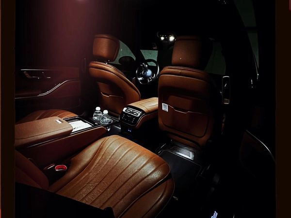 Luxurious brown leather car interior with ambient lighting and bottled water.