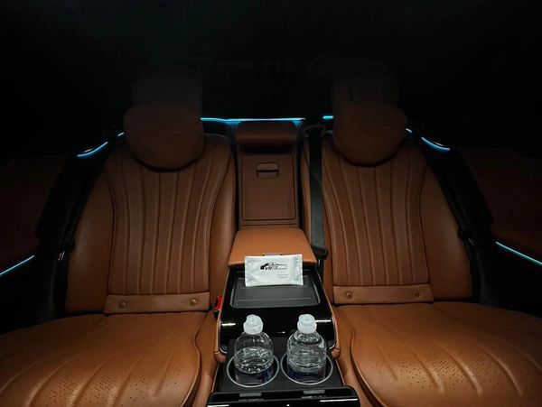 Luxurious brown leather rear seats with ambient lighting in a car.