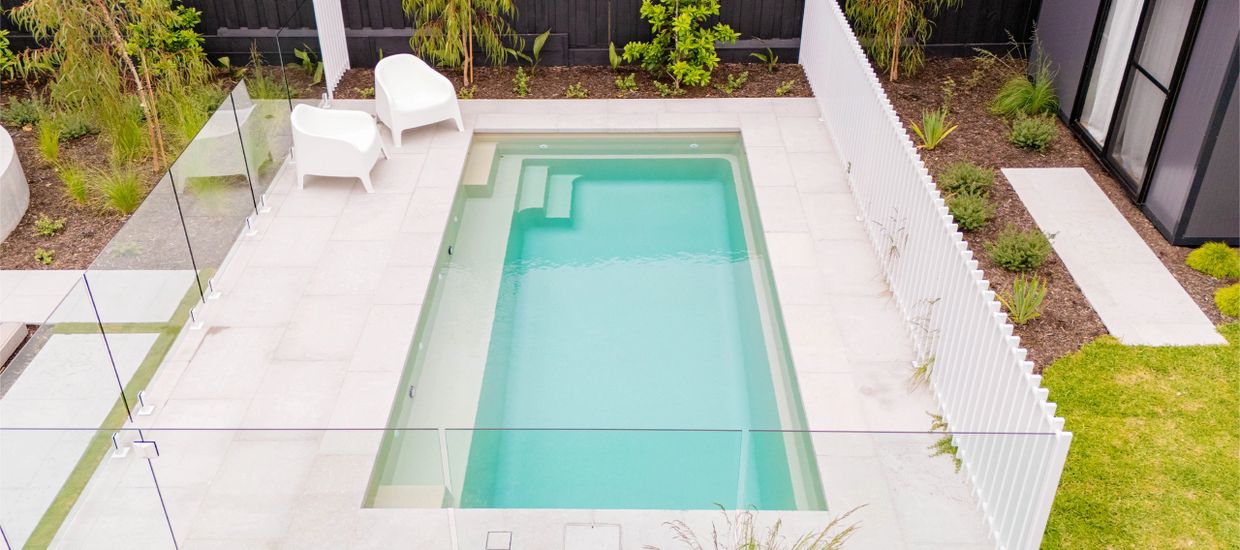 Modern backyard with a sleek rectangular pool and white lounge chairs.