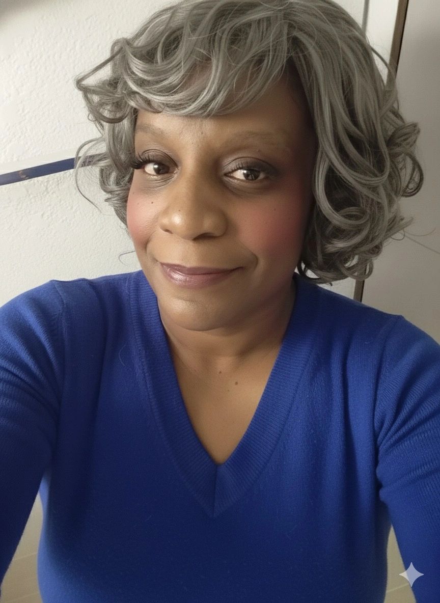 Smiling woman with curly gray hair and blue sweater.