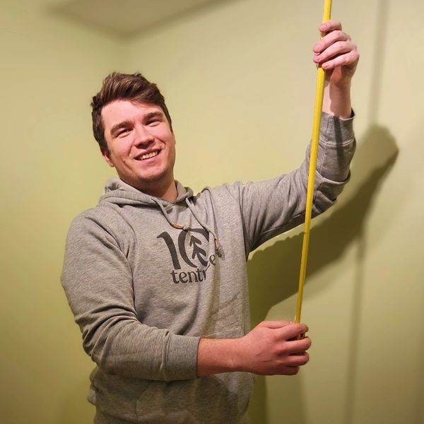 Smiling man holding a long yellow object.