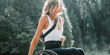 Image of a person in a wheelchair against a backdrop of evergreen trees. Photo: Zachary Kyra Derksen