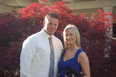 Couple posing outdoors with vibrant red foliage in the background.