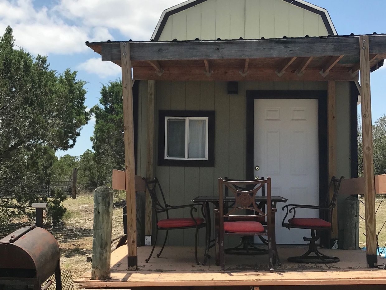 Rustic cabin porch with chairs and table.