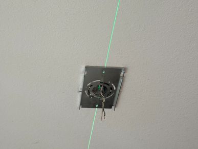 Ceiling mounting bracket with wires and a green laser line.