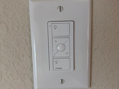 White Lutron dimmer switch on textured beige wall.