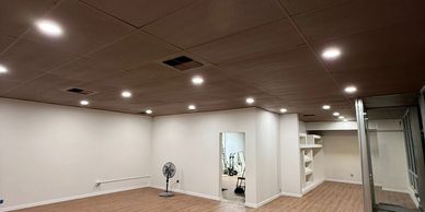 Empty room with wooden floor and white walls under recessed lighting.