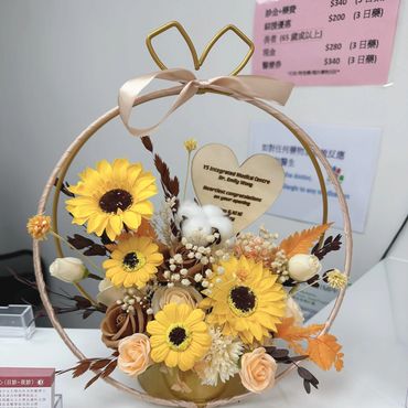Elegant floral arrangement with sunflowers and roses in a circular frame with a congratulatory note.