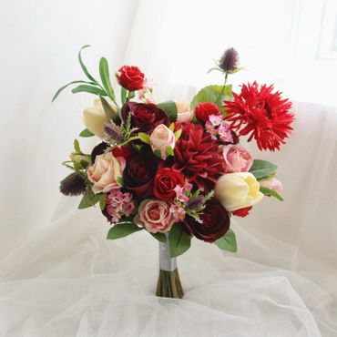 A vibrant bouquet of mixed flowers with red, pink, and cream tones.