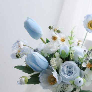 Delicate bouquet of pale blue and white flowers with green foliage.