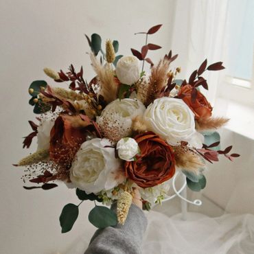 Elegant bouquet with white and rust-colored flowers and greenery.