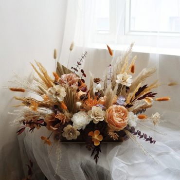 Elegant dried floral arrangement with neutral and warm tones by a window.